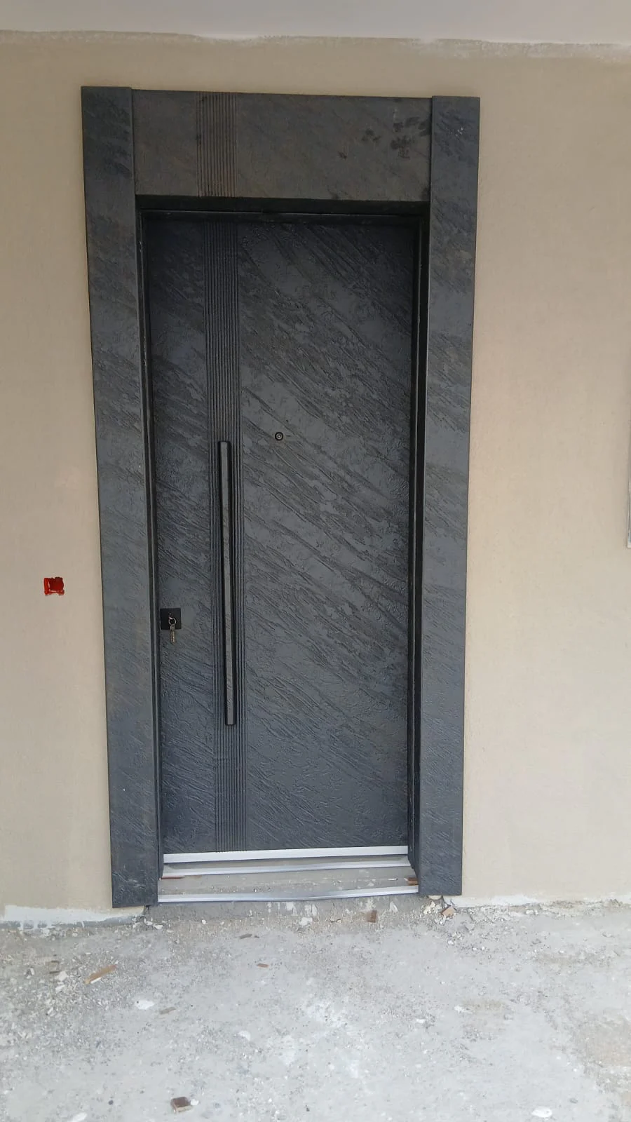 Hedef Door HD-CK009 antrasit dokulu zırhlı kapı, uzun siyah kol ve düşey çizgili panelin gerçek uygulama fotoğrafı